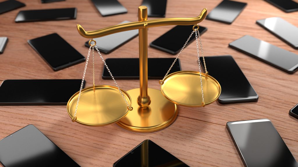 The scales of justice surrounded by an array of smartphones.