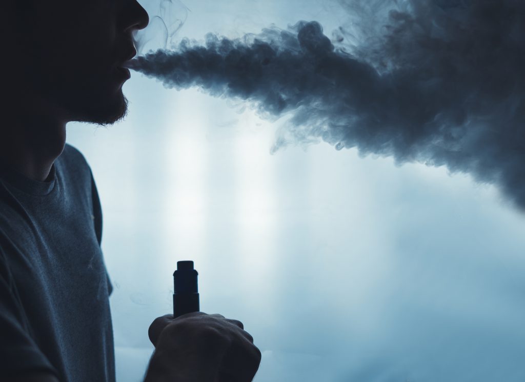 A man exhales steam from his electronic cigarette