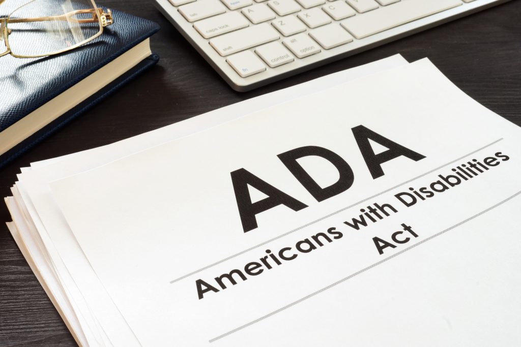 A stack of papers, with the top paper reading "ADA" in large brint. Below that, in smaller print, reads "Americans with Disabiltiies Act"