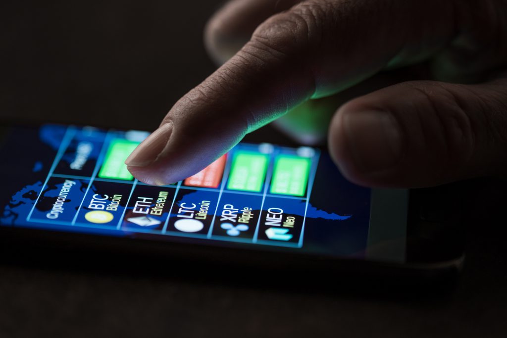 A finger browsing cryptocurrency prices on a smartphone app.