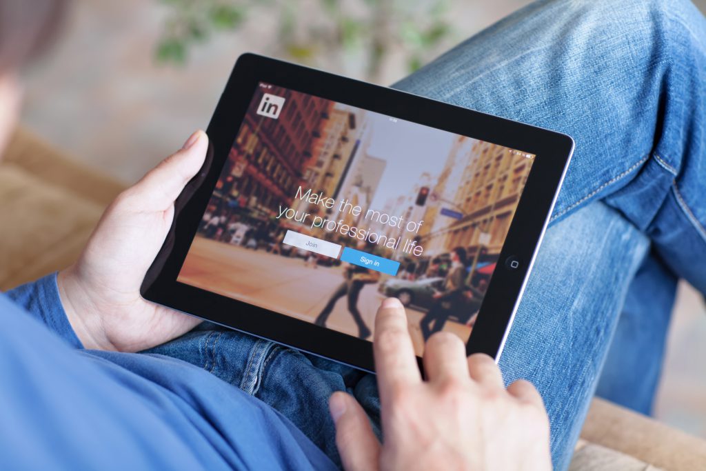 Person holding tablet with LinkedIn app open