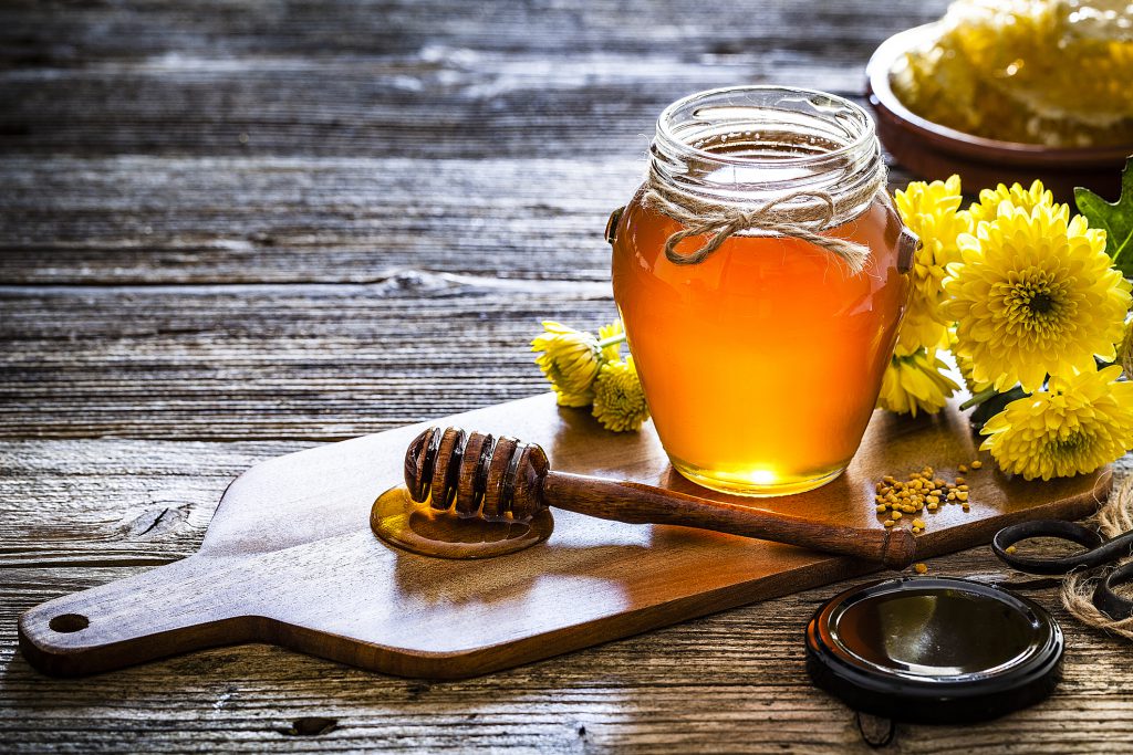 Honey jar with honey dipper on a table