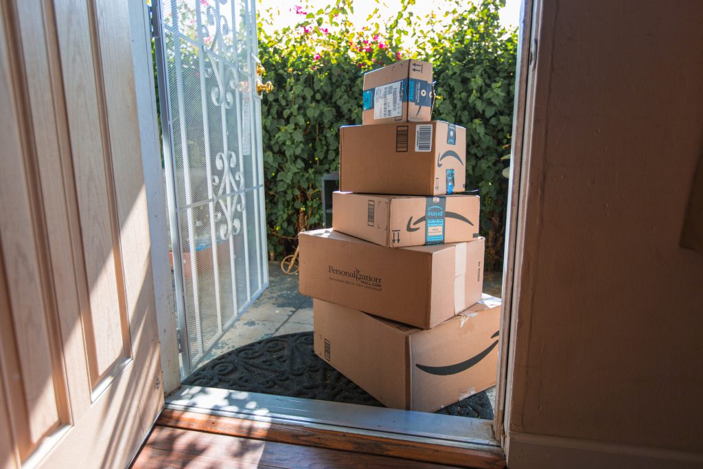 A stack of Amazon packages on a front porch.