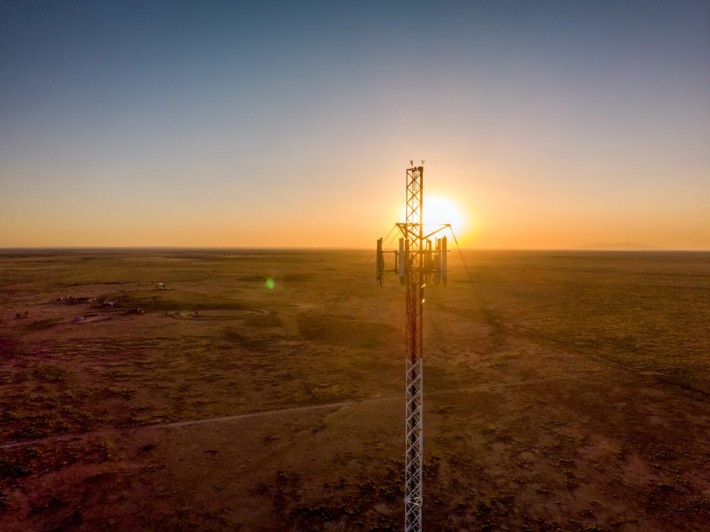A cell tower overlooking a landscape at sunset.